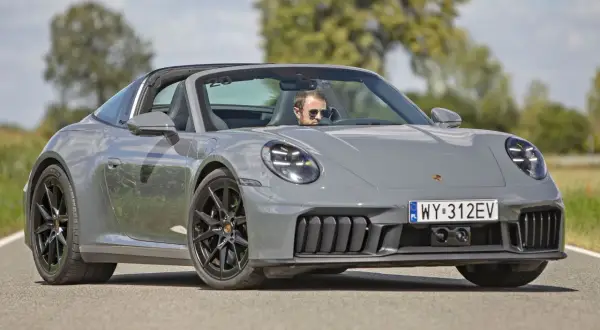 Szary Porsche 911 Targa z otwartym dachem, kierowca w okularach przeciwsłonecznych. Sprawdź porsche 911 cena!