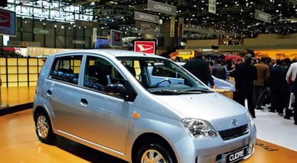 Srebrny Daihatsu Cuore na targach motoryzacyjnych, wśród tłumu ludzi i innych stoisk.