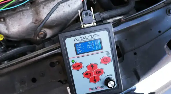 Tester diagnostyczny mierzy moc alternatora samochodowego, pokazując napięcie i inne parametry.