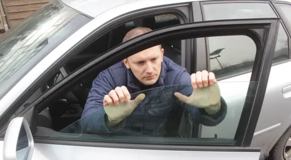 Mężczyzna próbuje podnieść szybę elektryczną w samochodzie, która nie chce się podnieść.
