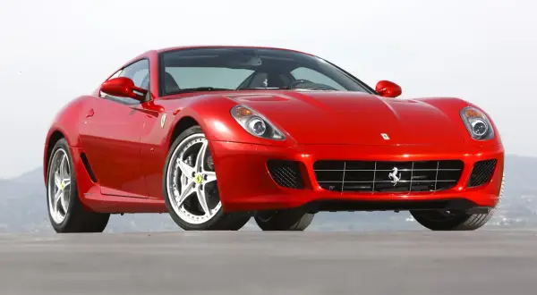 Czerwone Ferrari 599, błyszczące w słońcu, z charakterystycznym grillem i felgami. Marzenie każdego miłośnika motoryzacji.