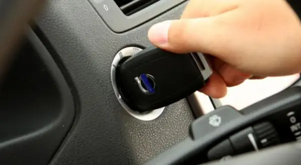 Dłoń wkłada kluczyk do stacyjki. To pokazuje, jak działa immobilizer, zabezpieczając auto przed kradzieżą.