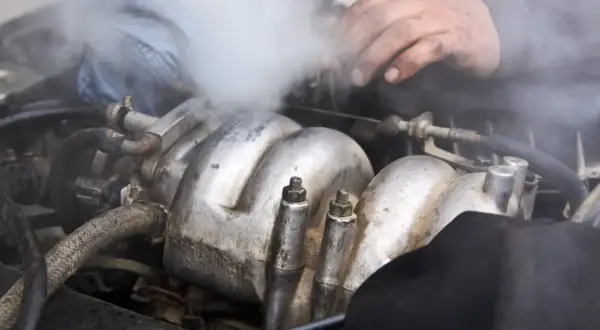 Para wylatuje z silnika. Czy można wlać płyn chłodniczy do ciepłego silnika? Mechanik sprawdza problem.