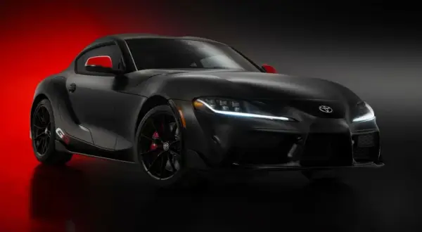 Czarna Toyota Supra GR z czerwonymi akcentami na lusterkach i zaciskach hamulcowych, prezentująca sportowy design.