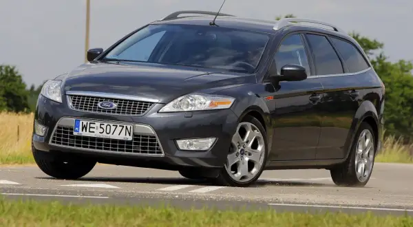 Ciemnoszary Ford Mondeo MK4 2.0 TDCI na drodze, z widocznym polem zboża w tle.
