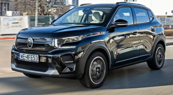 Czarny Citroën C3 Aircross pędzi ulicami miasta, odbijając w swojej lśniącej karoserii miejski krajobraz.