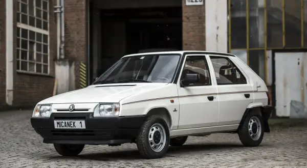 Biały Skoda Favorit z lat 90. na tle ceglanego budynku.