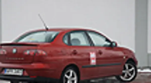 Czerwony Seat Cordoba z naklejką na drzwiach, zaparkowany na zewnątrz.