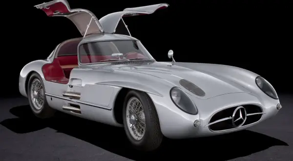 Srebrny Mercedes 300 SL Gullwing z otwartymi drzwiami, czerwone wnętrze, klasyk motoryzacji.