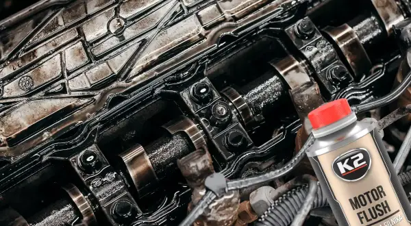 Zabrudzony silnik samochodowy i butelka K2 Motor Flush – dobra płukanka do silnika, która przywróci mu czystość i sprawność.