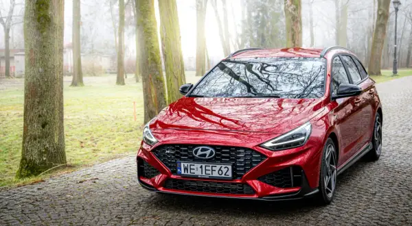 Czerwony Hyundai i30 Wagon N Line na kamienistej drodze w mglistym parku.