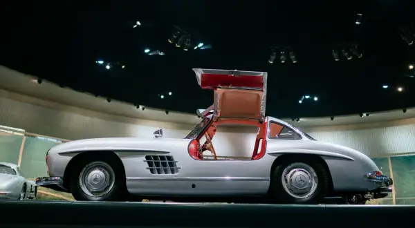 Srebrny Mercedes 300 SL z charakterystycznymi drzwiami otwieranymi do góry, prezentowany w muzeum.