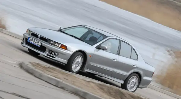 Srebrny Mitsubishi Galant z gracją pokonuje zakręt.