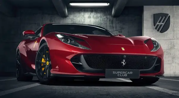 Czerwone Ferrari 812 GTS z żółtymi zaciskami hamulcowymi stoi w garażu.