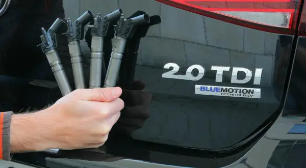 Dłoń trzyma cztery wtryskiwacze do silnika common rail 2.0 TDI.