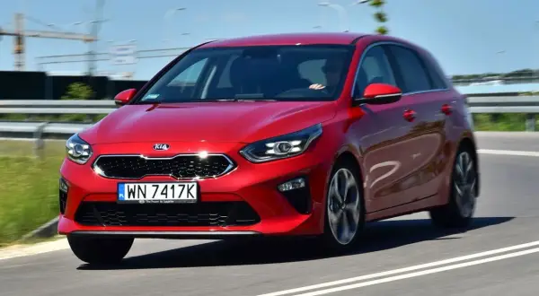 Czerwony Kia Ceed 1.4 benzyna w ruchu drogowym. Elegancki hatchback z dynamicznym wyglądem.