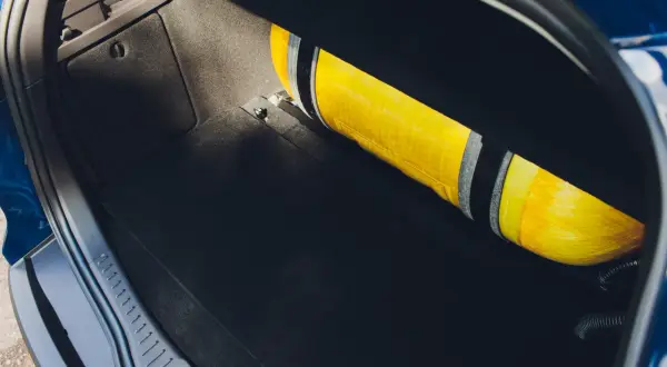 Żółta butla LPG zamontowana w bagażniku samochodu.