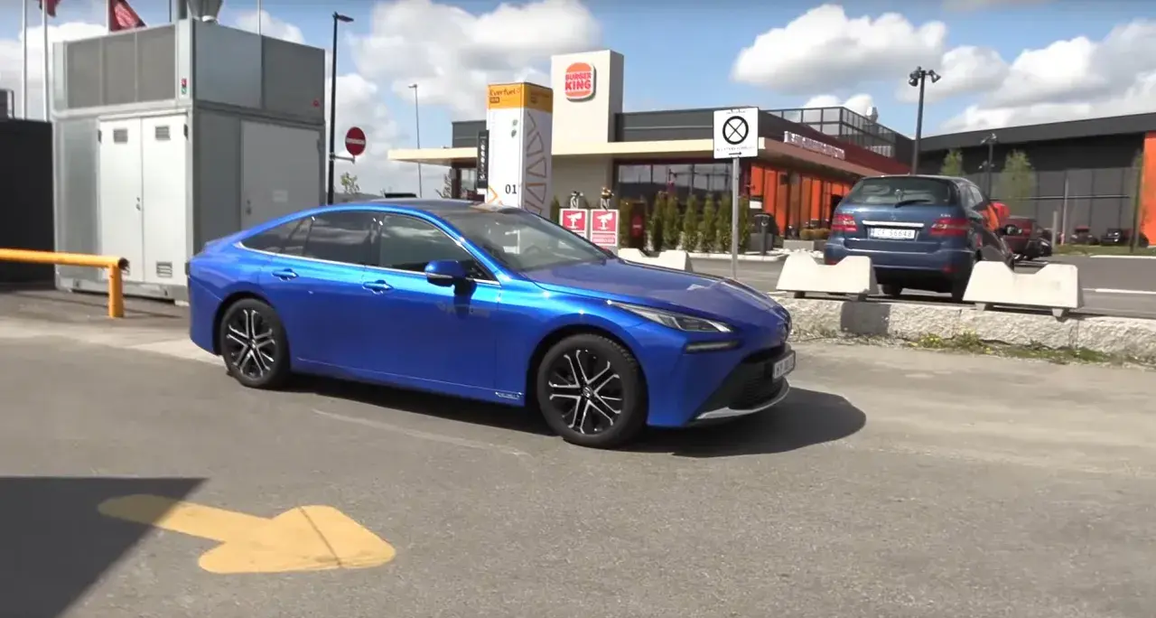 Niebieska Toyota Mirai, samochód wodorowy, parkuje obok stacji paliw. Sprawdzamy, jaka jest toyota mirai cena.