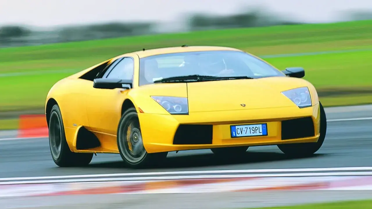 Żółty Lamborghini Murcielago pędzi po torze wyścigowym, zostawiając za sobą rozmyte zielone krajobrazy.