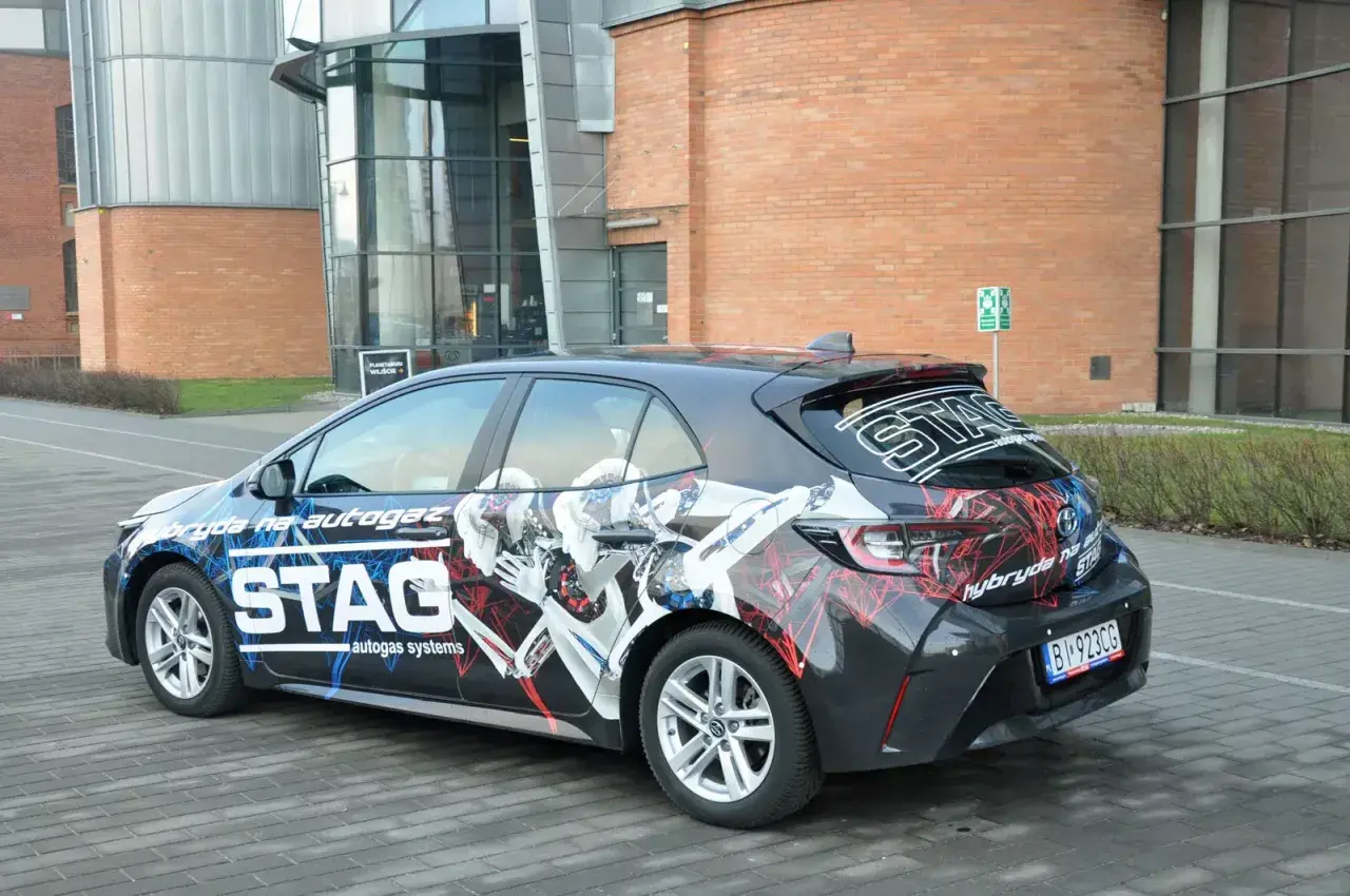 Samochód hybrydowy z grafiką STAG, informującą o paliwie: cng i hybryda. Nowoczesny design podkreśla ekologiczny napęd.