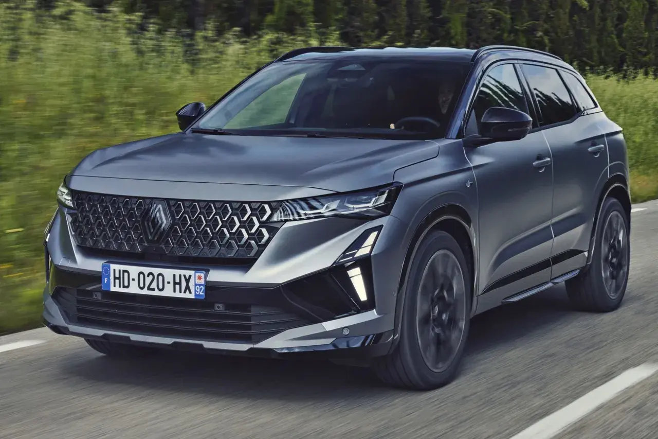 Nowy Renault Austral 2025 w ciemnoszarym kolorze pędzi po drodze, otoczony zielenią.