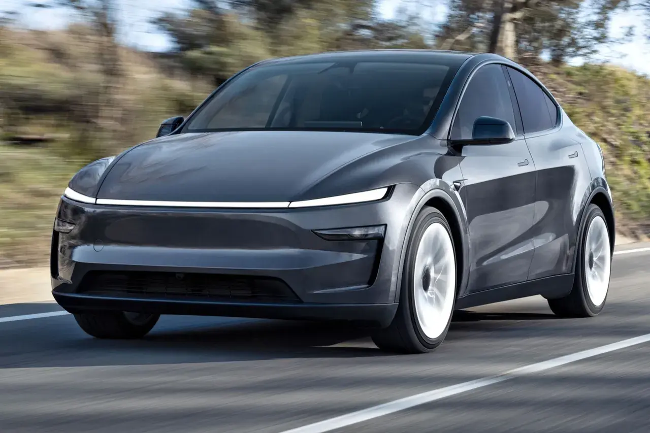 Szary Tesla SUV pędzi po drodze, otoczony rozmytym krajobrazem.