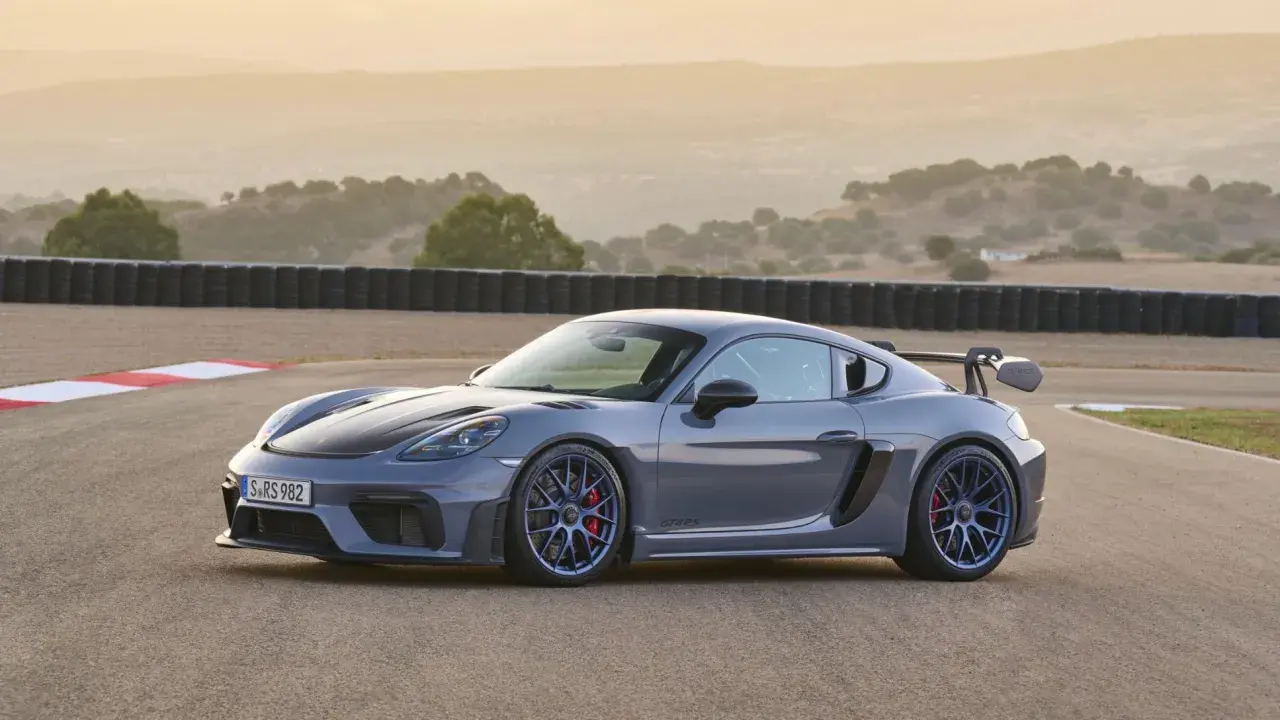 Szary Porsche GT4 RS na torze wyścigowym, z charakterystycznym skrzydłem i niebieskimi felgami.
