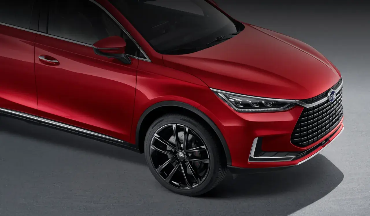 Czerwony BYD Tang błyszczy na ciemnym tle, prezentując eleganckie linie i sportowe felgi.