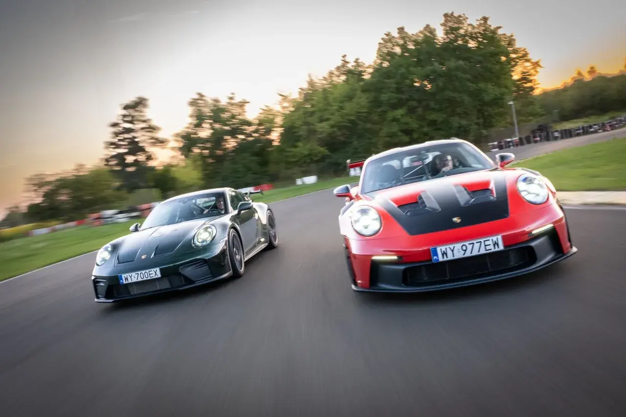 Dwa Porsche GT3, czerwone i zielone, ścigają się na torze wyścigowym.
