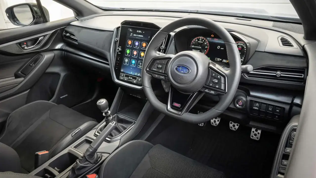 Wnętrze Subaru STI z dużym ekranem dotykowym, cyfrowymi zegarami i sportową kierownicą. Gotowy na jazdę!