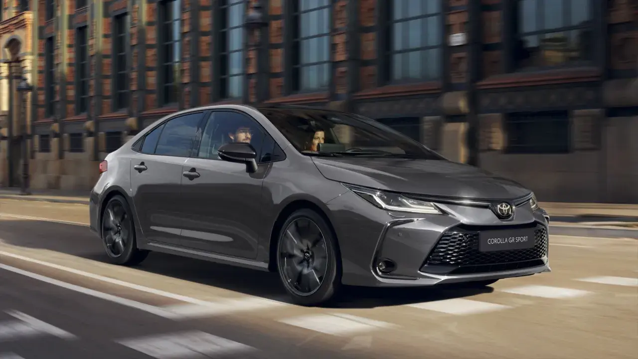 Szara Toyota Corolla GR Sport jedzie ulicą miasta. W środku siedzi para.