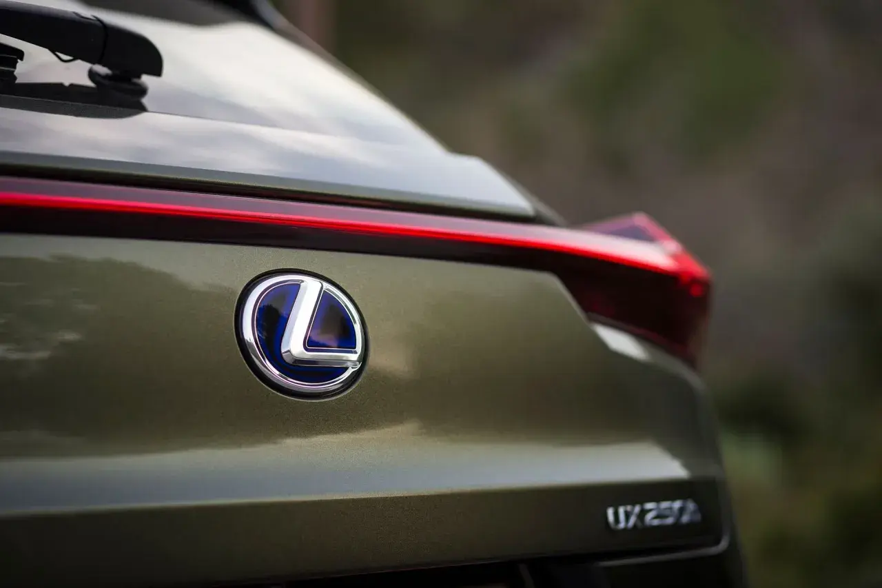 Tylna część Lexusa UX 250h w kolorze oliwkowym. Widoczne logo marki i nazwa modelu. Poznaj lexus ux wymiary.