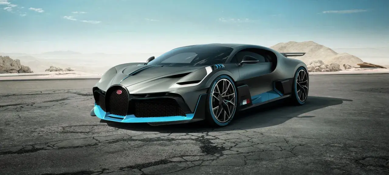 Szary Bugatti Divo z niebieskimi akcentami na pustynnej drodze.