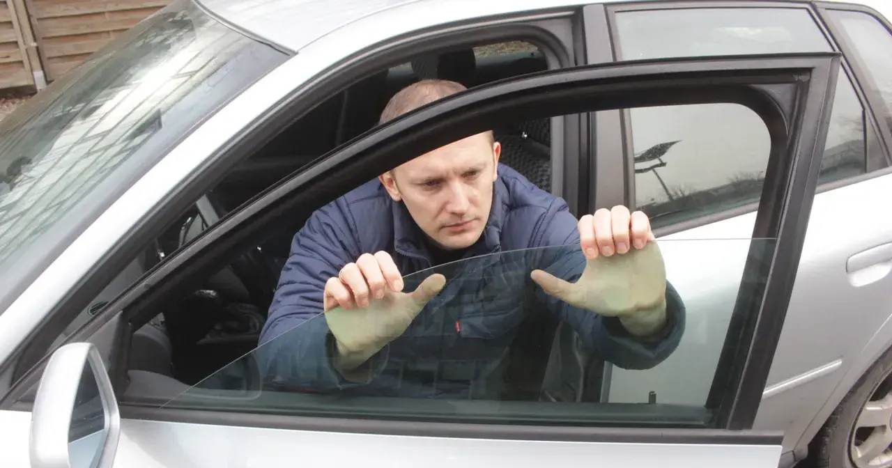 Mężczyzna próbuje podnieść szybę elektryczną w samochodzie, która nie chce się podnieść.