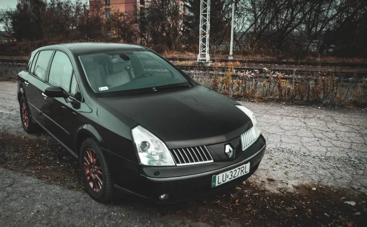 Czarny Renault Vel Satis z miedzianymi felgami stoi przy torach kolejowych.