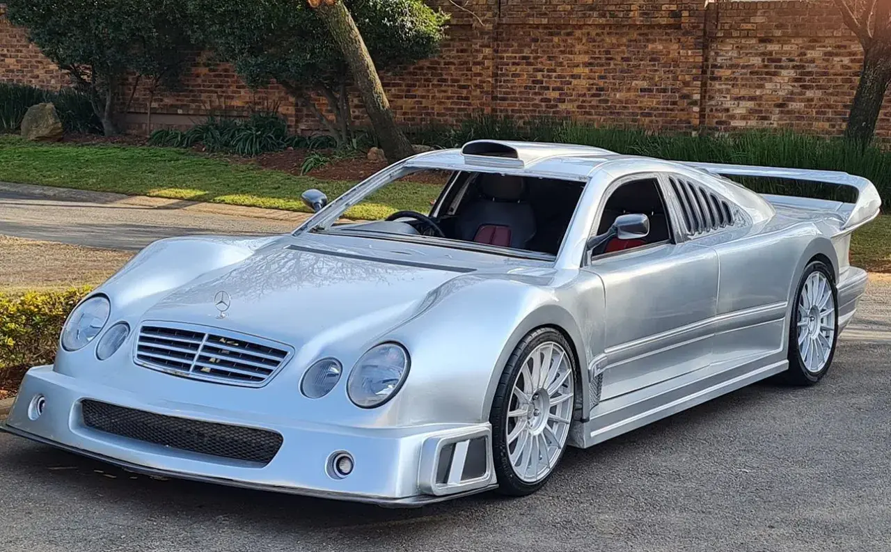 Srebrny Mercedes CLK GTR z masywnym spojlerem i wlotem powietrza na dachu, gotowy do wyścigu.