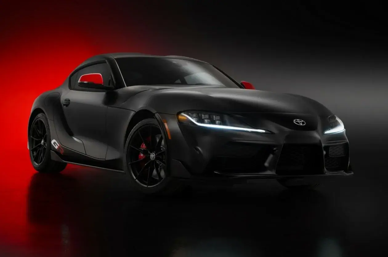 Czarna Toyota Supra GR z czerwonymi akcentami na lusterkach i zaciskach hamulcowych, prezentująca sportowy design.