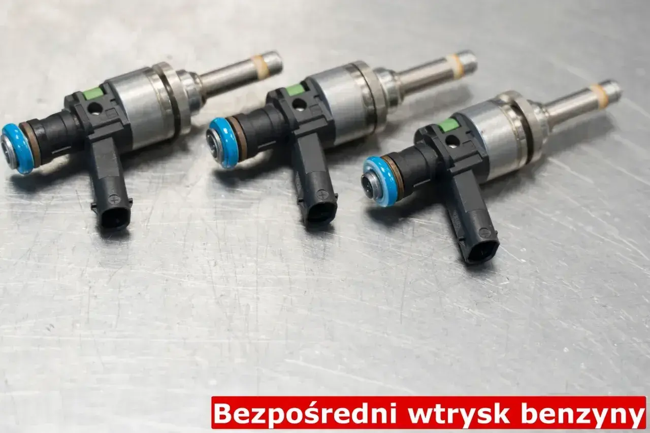 Trzy wtryskiwacze paliwa do silnika z bezpośrednim wtryskiem benzyny (GDI) na metalowej powierzchni.