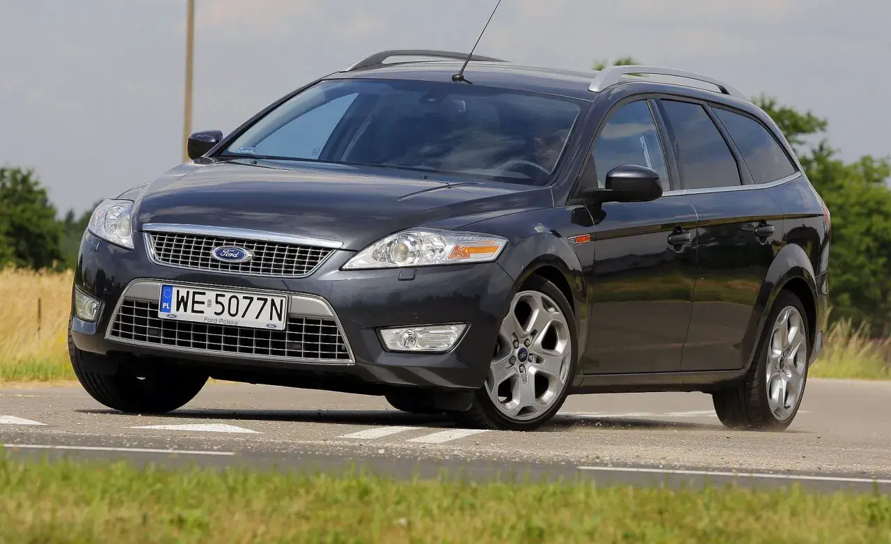 Ciemnoszary Ford Mondeo MK4 2.0 TDCI na drodze, z widocznym polem zboża w tle.