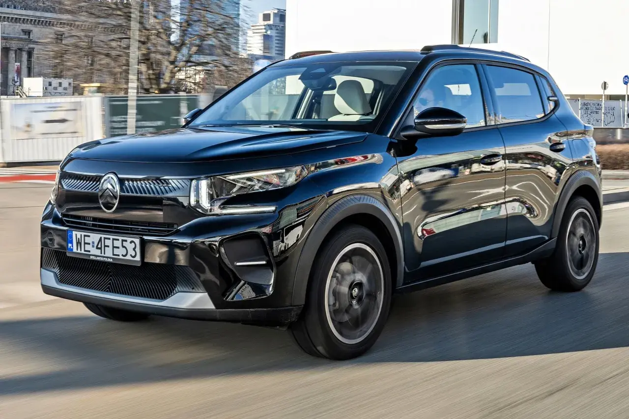 Czarny Citroën C3 Aircross pędzi ulicami miasta, odbijając w swojej lśniącej karoserii miejski krajobraz.