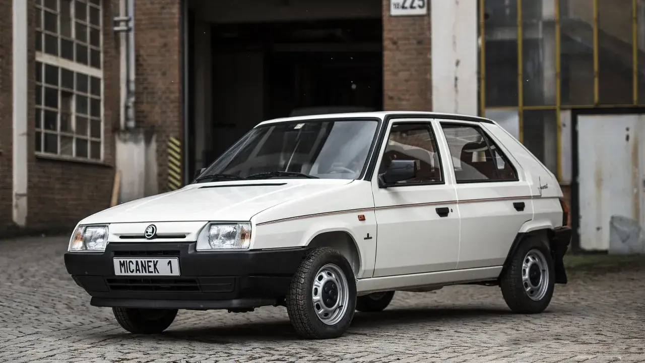 Biały Skoda Favorit z lat 90. na tle ceglanego budynku.