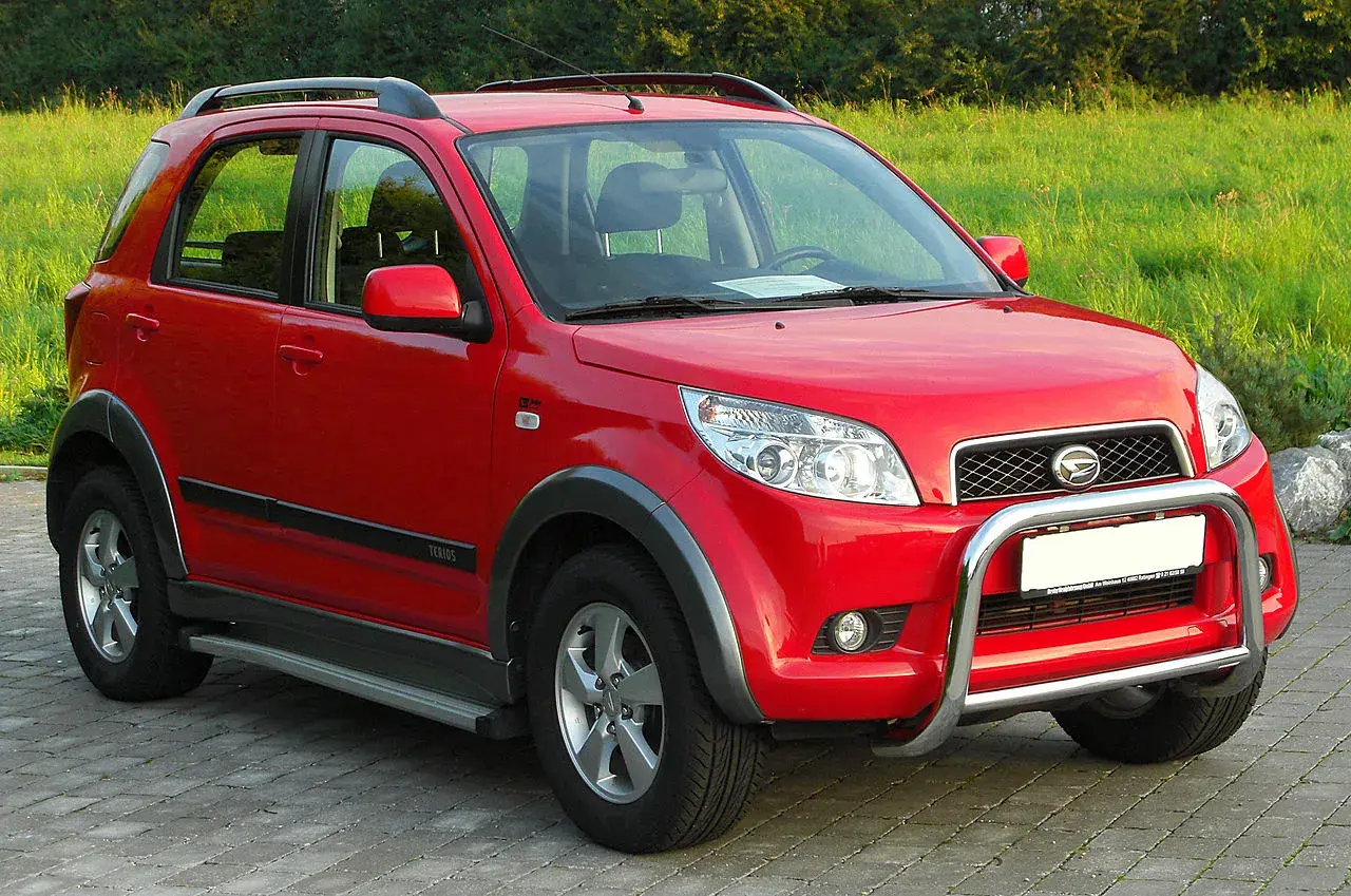 Czerwony Daihatsu Terios z metalowym orurowaniem z przodu, gotowy na przygodę.