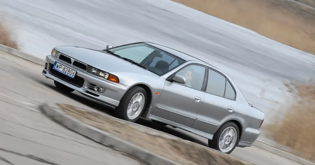 Srebrny Mitsubishi Galant z gracją pokonuje zakręt.