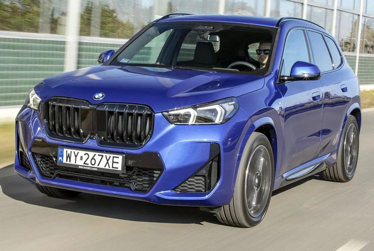 Niebieskie BMW X1 w ruchu. Zwróć uwagę na jego dynamiczne linie i kompaktowe bmw x1 wymiary, idealne do miasta.