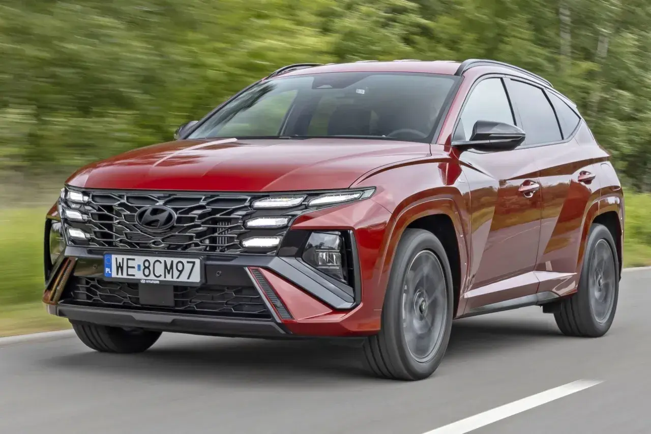 Czerwony Hyundai Tucson z charakterystycznym grillem i światłami LED pędzi po drodze. TCO.