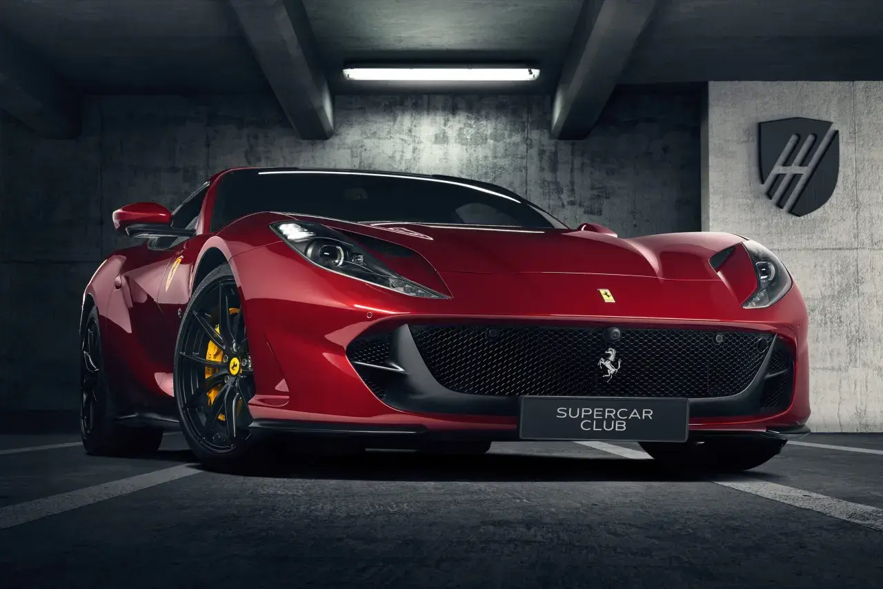 Czerwone Ferrari 812 GTS z żółtymi zaciskami hamulcowymi stoi w garażu.