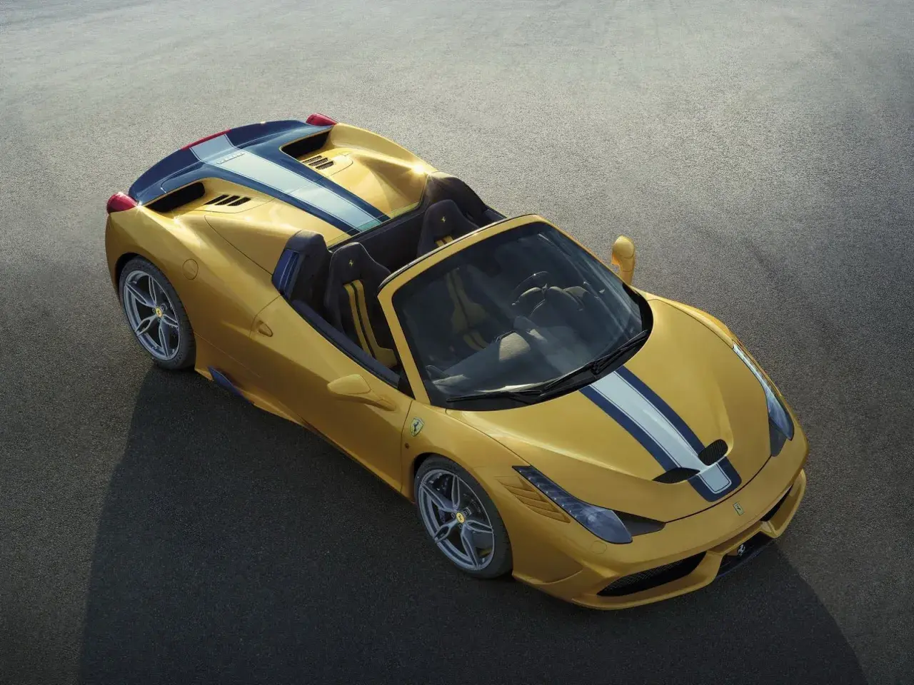 Żółte Ferrari 458 Spider z niebiesko-białymi pasami na masce i tyle, gotowe do jazdy po torze.