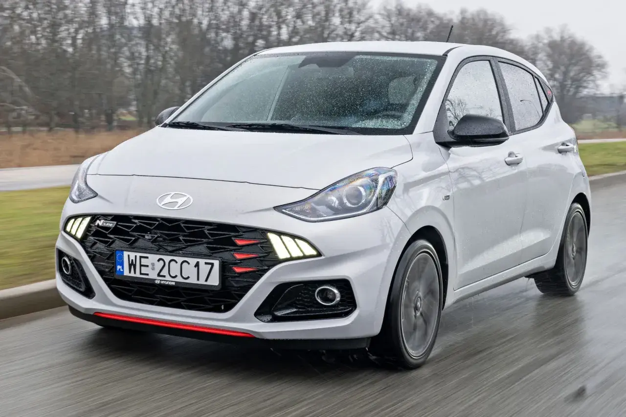Biały Hyundai i10 N Line w ruchu, z widocznym grillem i światłami LED. Sprawdź aktualną hyundai i10 cena.