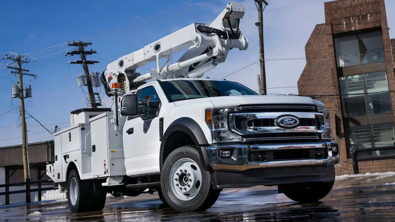 Biały Ford F650 z podnośnikiem koszowym, gotowy do pracy przy liniach energetycznych.