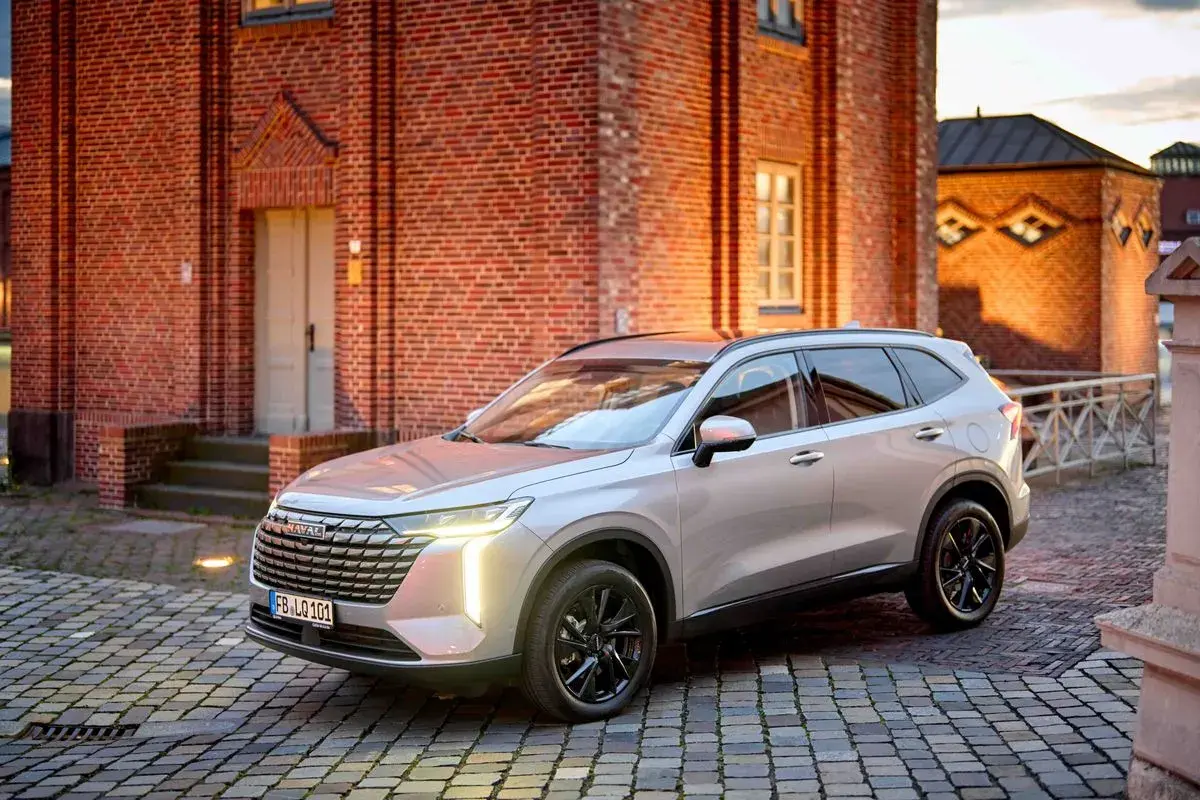 Srebrny Haval na brukowanej ulicy przed ceglanym budynkiem.